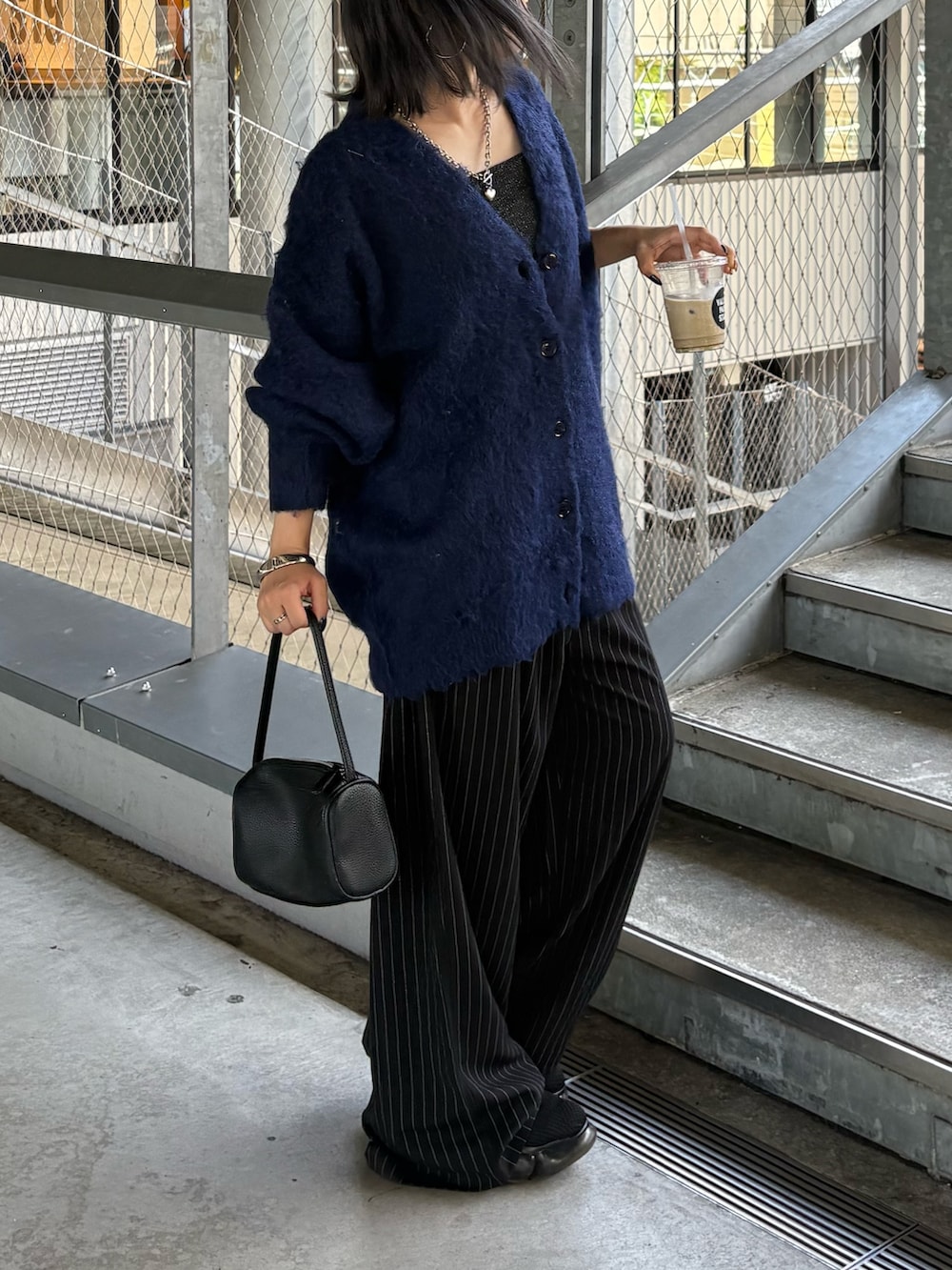 ブルー系のカーディガン/ボレロ、ブラック系のハンドバッグ、ブラック系のスラックスを着用したレディースの秋コーディネートの2枚目の写真