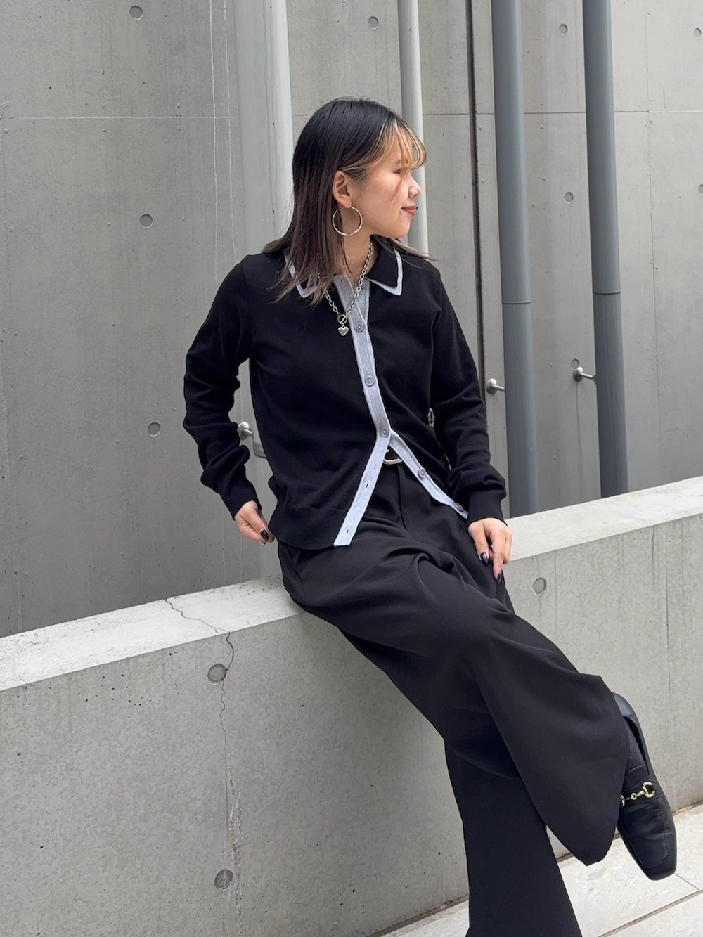 ブラック系のスラックス、ホワイト系のハンドバッグ、ブラック系のカーディガン/ボレロを着用したレディースの冬コーディネートの3枚目の写真