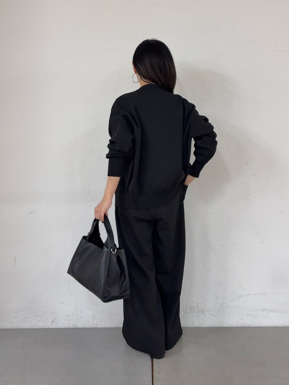 ブラック系のスラックス、ブラック系のハンドバッグ、ブラック系のキャミソールを着用したレディースの春コーディネートの3枚目の写真