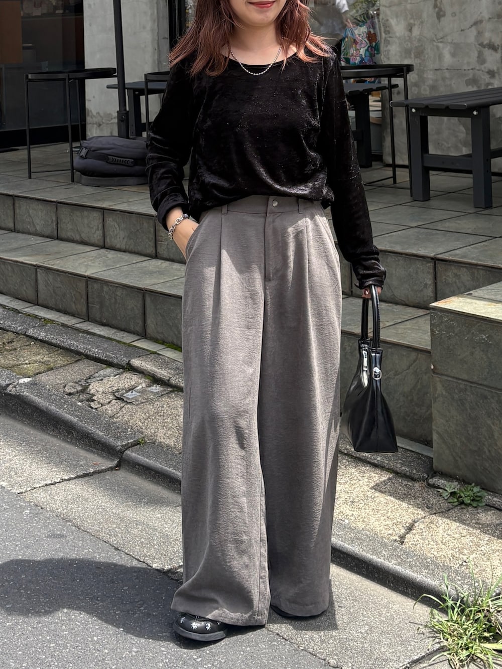 グレー系のスラックス、ブラック系のトートバッグ、ブラック系のTシャツ/カットソーを着用したレディースの夏コーディネートの4枚目の写真