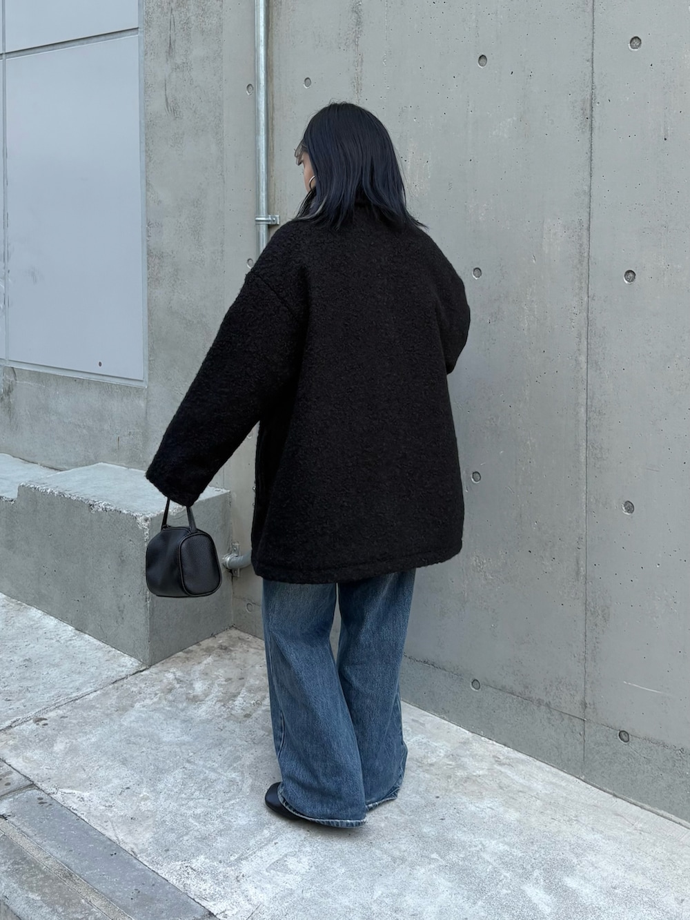 ブラック系のハンドバッグ、グレー系のカーディガン/ボレロ、ブルー系のデニムパンツを着用したレディースの秋コーディネートの3枚目の写真