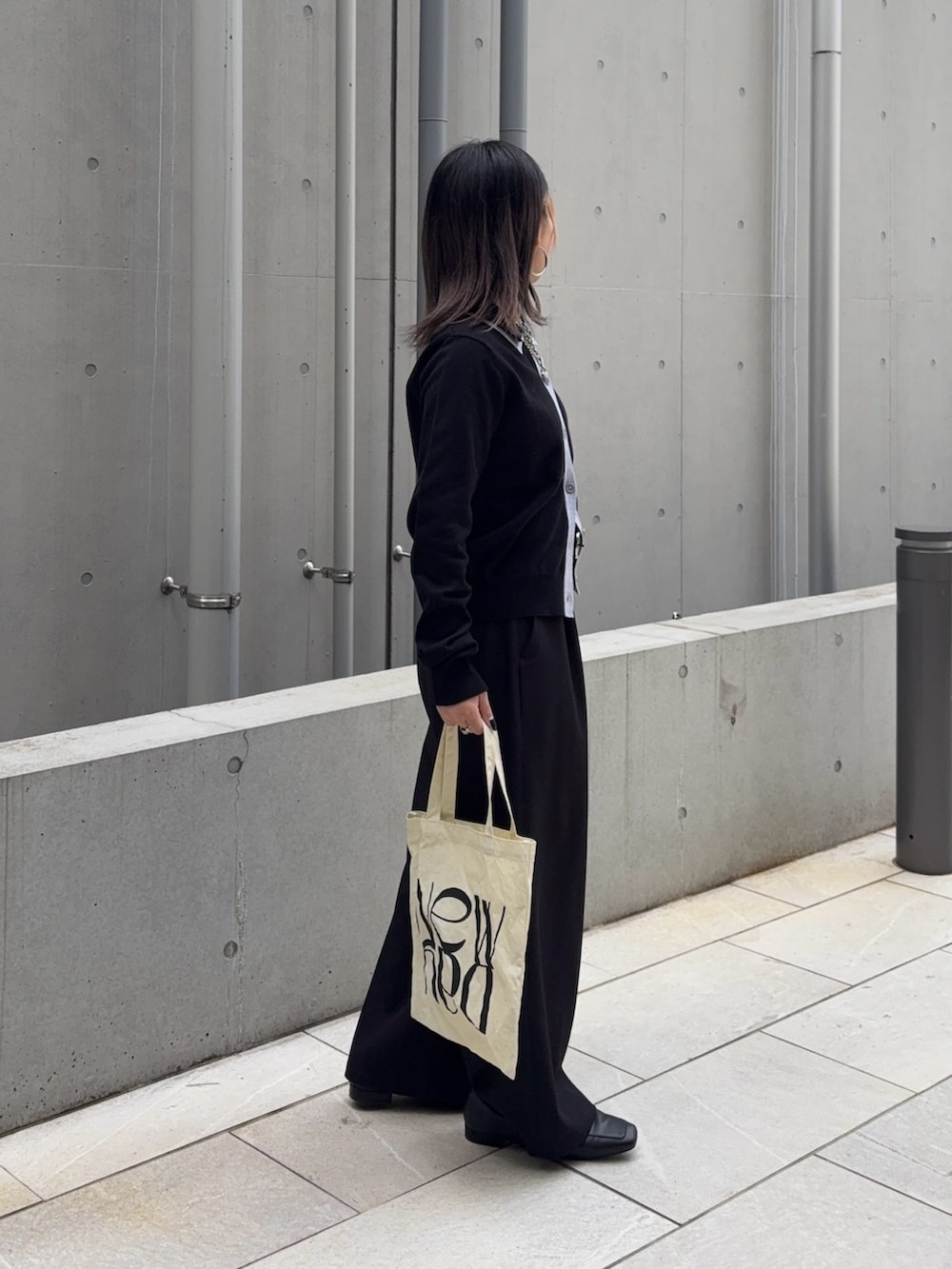 ブラック系のスラックス、ホワイト系のハンドバッグ、ブラック系のカーディガン/ボレロを着用したレディースの冬コーディネートの4枚目の写真