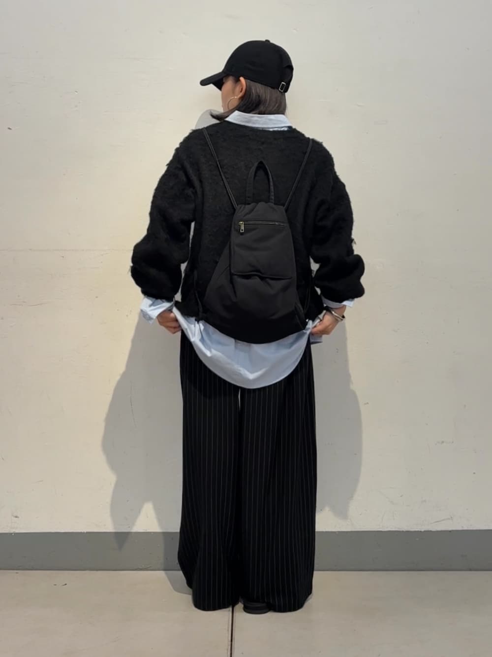 ブラック系のニット/セーター、ブルー系のシャツ/ブラウス、ブラック系のサンダルを着用したレディースの秋コーディネートの3枚目の写真