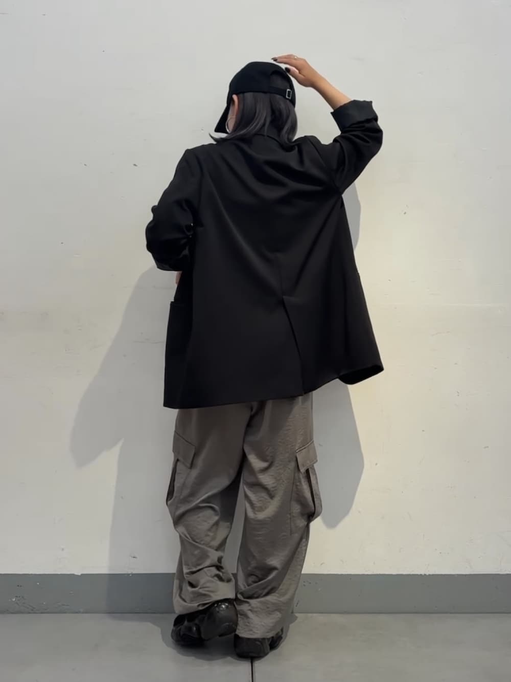 グレー系のカーゴパンツ、ブラック系のテーラードジャケット、ブラック系のキャップを着用したレディースの秋コーディネートの3枚目の写真