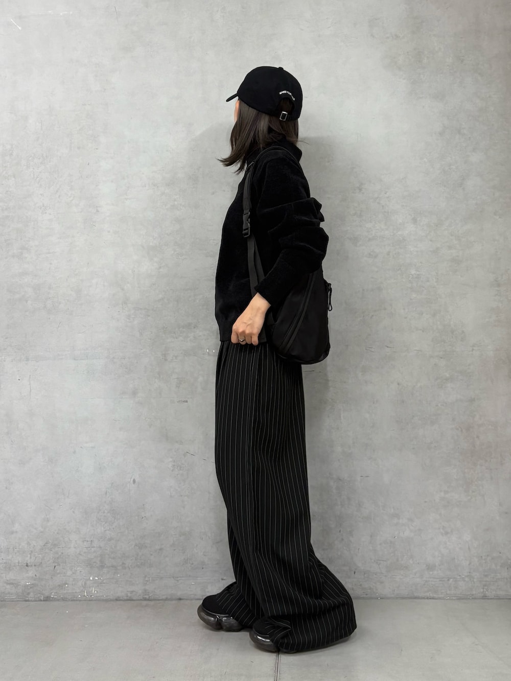 ブラック系のスラックス、ブラック系のボディバッグ/ウエストポーチ、ブラック系のニット/セーターを着用したレディースの秋コーディネートの2枚目の写真