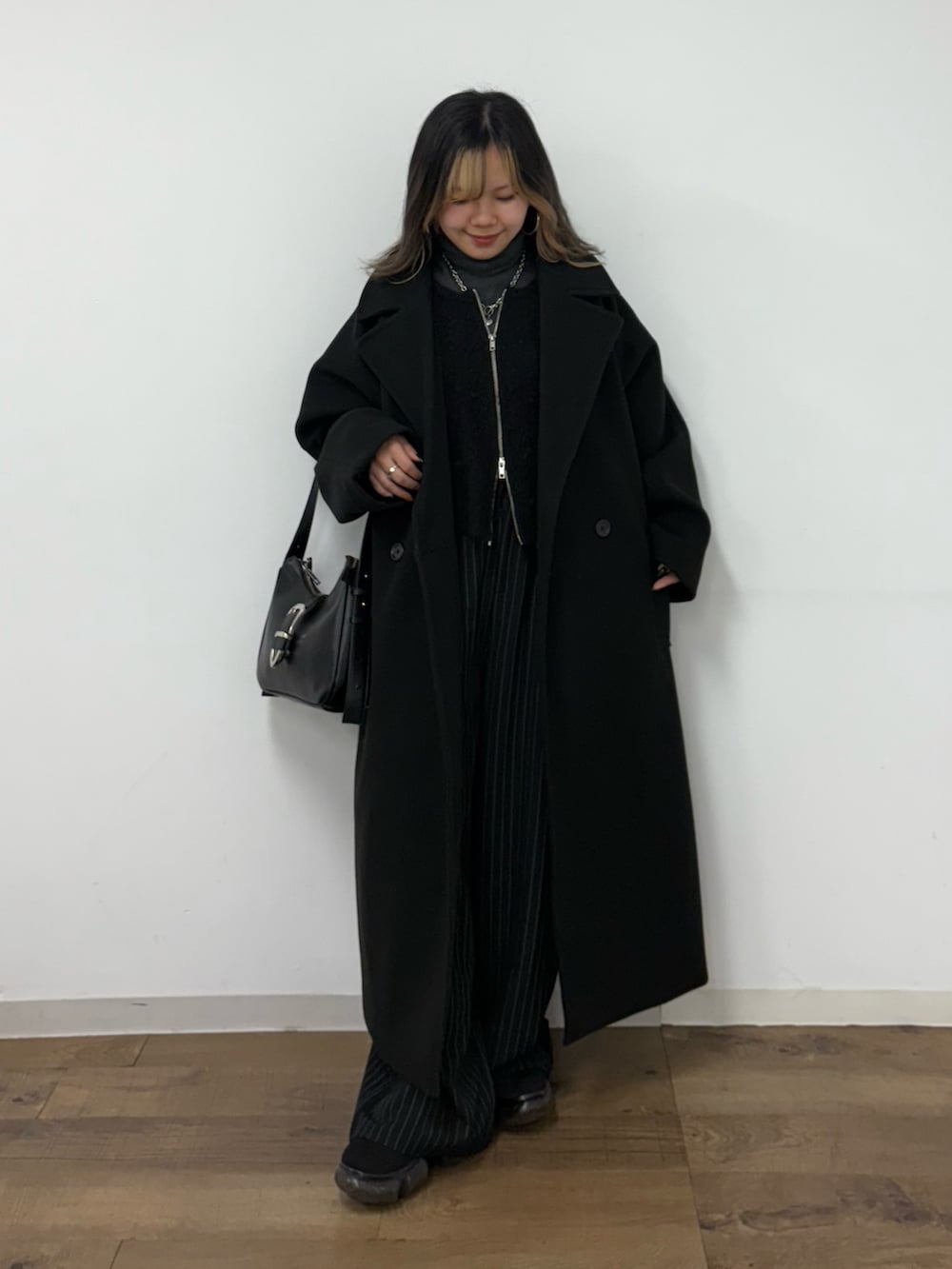 ブラック系のチェスターコート、ブラック系のショルダーバッグ、ブラック系のカーディガン/ボレロを着用したレディースの冬コーディネートの2枚目の写真