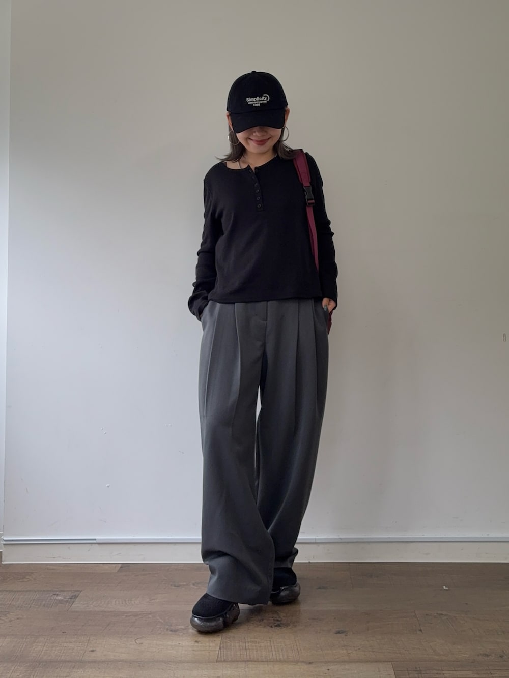 グレー系のスラックス、レッド系のボディバッグ/ウエストポーチ、ブラック系のTシャツ/カットソーを着用したレディースの秋コーディネートの5枚目の写真