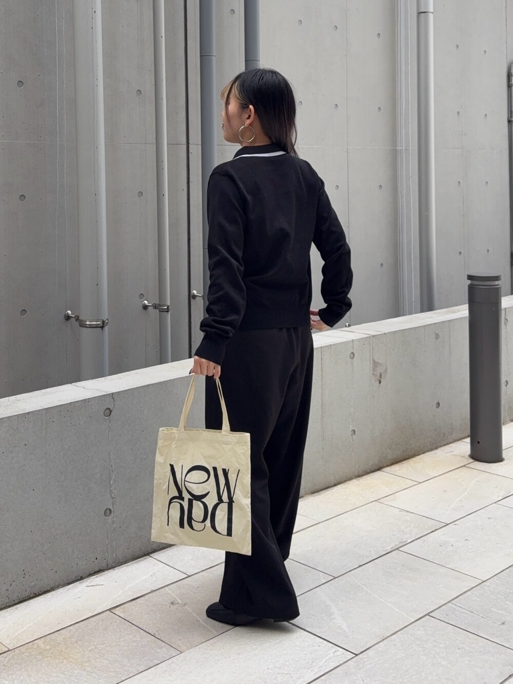 ブラック系のスラックス、ホワイト系のハンドバッグ、ブラック系のカーディガン/ボレロを着用したレディースの冬コーディネートの5枚目の写真