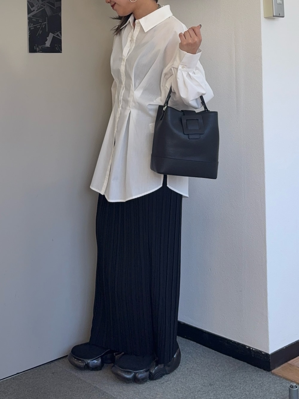 ブラック系のスカート、ブラック系のショルダーバッグ、ホワイト系のシャツ/ブラウスを着用したレディースの春コーディネートの2枚目の写真