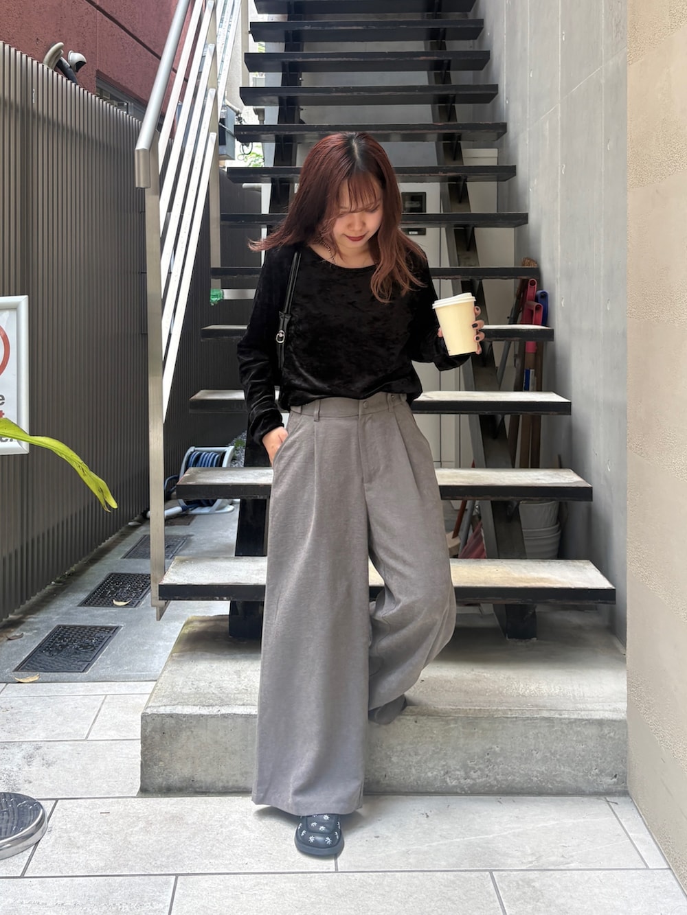 グレー系のスラックス、ブラック系のトートバッグ、ブラック系のTシャツ/カットソーを着用したレディースの夏コーディネートの2枚目の写真