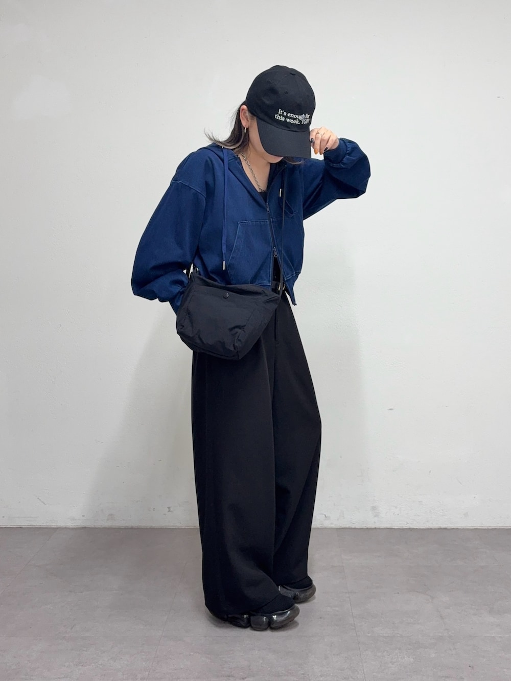 ブラック系のスラックス、ブラック系のショルダーバッグ、ブルー系のパーカーを着用したレディースの冬コーディネートの2枚目の写真