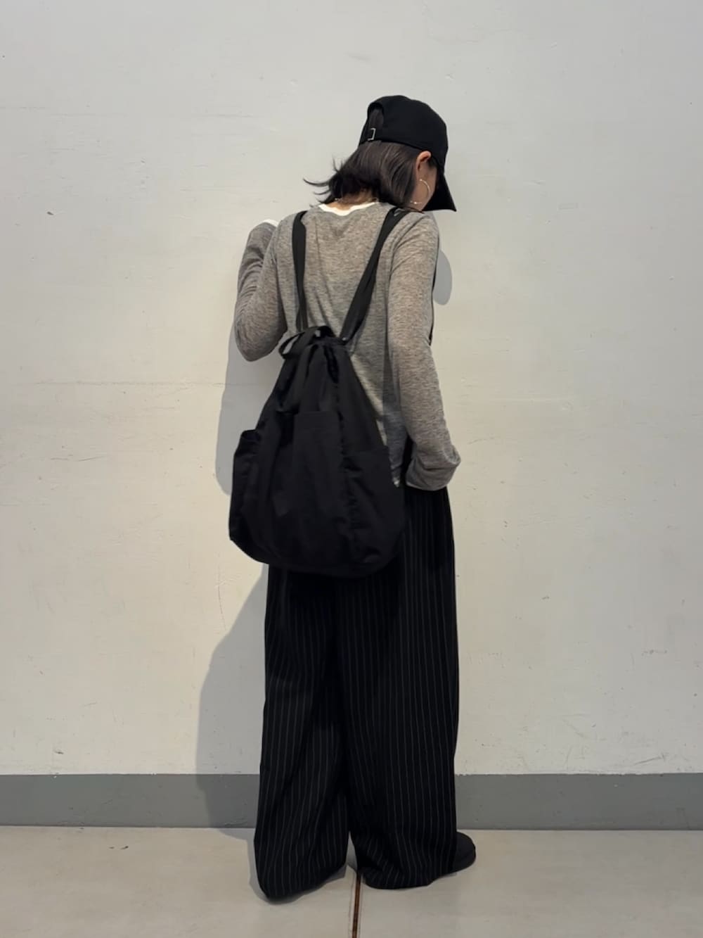 グレー系のTシャツ/カットソー、ブラック系のバックパック/リュック、ブラック系のスラックスを着用したレディースの秋コーディネートの3枚目の写真
