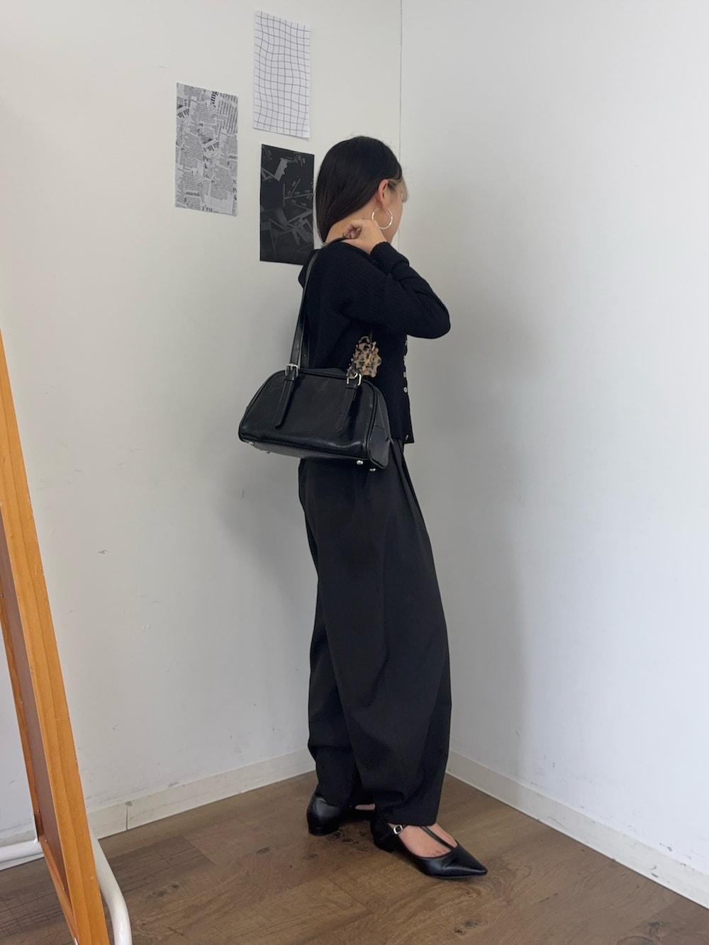 ブラック系のボストンバッグ、ブラック系のカーディガン/ボレロ、ブラック系のスラックスを着用したレディースの春コーディネートの2枚目の写真