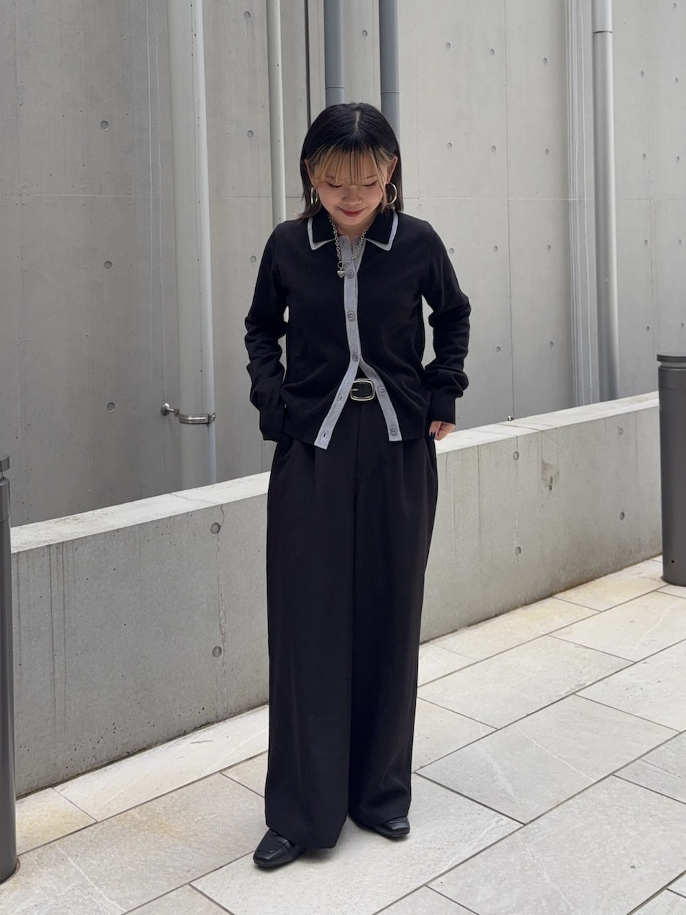 ブラック系のスラックス、ホワイト系のハンドバッグ、ブラック系のカーディガン/ボレロを着用したレディースの冬コーディネートの2枚目の写真