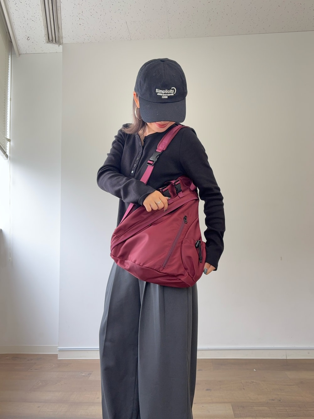 グレー系のスラックス、レッド系のボディバッグ/ウエストポーチ、ブラック系のTシャツ/カットソーを着用したレディースの秋コーディネートの4枚目の写真