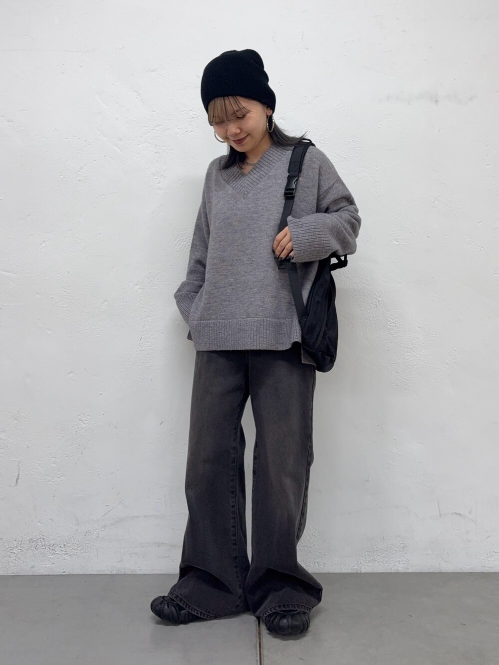 グレー系のニット/セーター、ブラック系のボディバッグ/ウエストポーチ、ブラック系のデニムパンツを着用したレディースの秋コーディネートの2枚目の写真