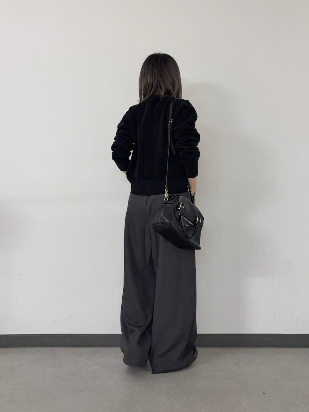 グレー系のスラックス、ブラック系のショルダーバッグ、ブラック系のカーディガン/ボレロを着用したレディースの秋コーディネートの3枚目の写真