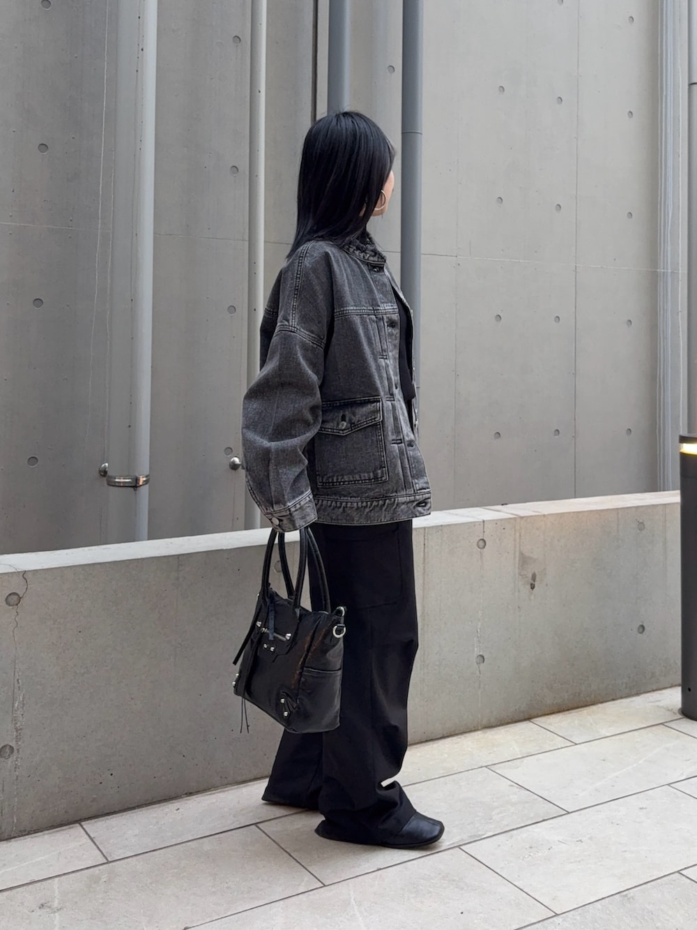 ブラック系のニット/セーター、ブラック系のデニムジャケット、ブラック系のショルダーバッグを着用したレディースの春コーディネートの2枚目の写真