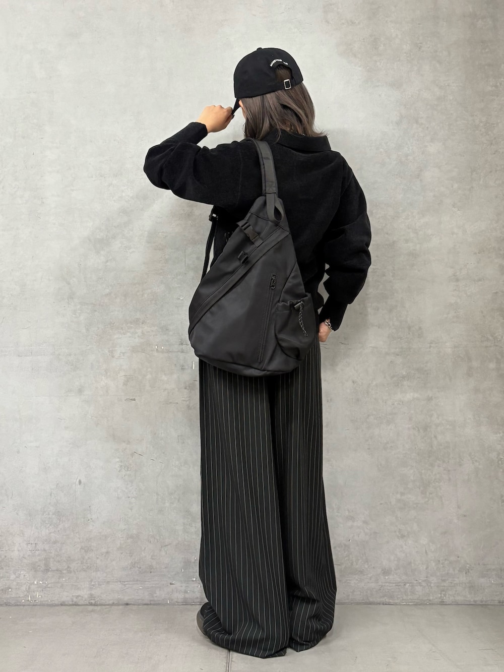 ブラック系のスラックス、ブラック系のボディバッグ/ウエストポーチ、ブラック系のニット/セーターを着用したレディースの秋コーディネートの3枚目の写真