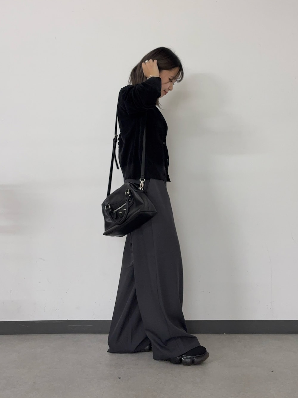 グレー系のスラックス、ブラック系のショルダーバッグ、ブラック系のカーディガン/ボレロを着用したレディースの秋コーディネートの2枚目の写真