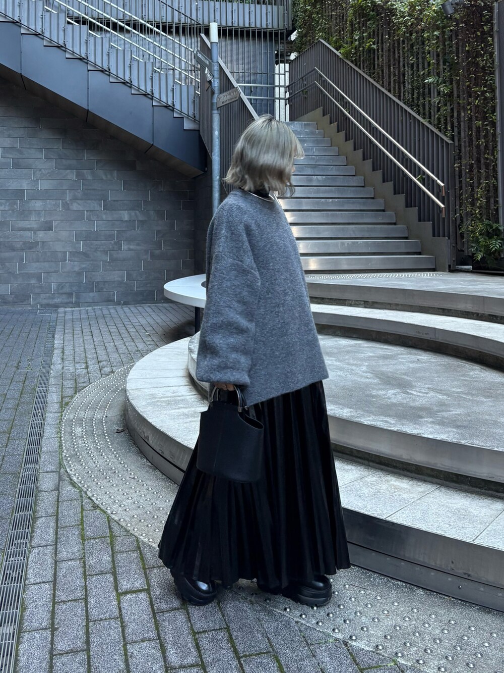 グレー系のニット/セーター、ブラック系のスカート、ブラック系のニット/セーターを着用したレディースの冬コーディネートの2枚目の写真