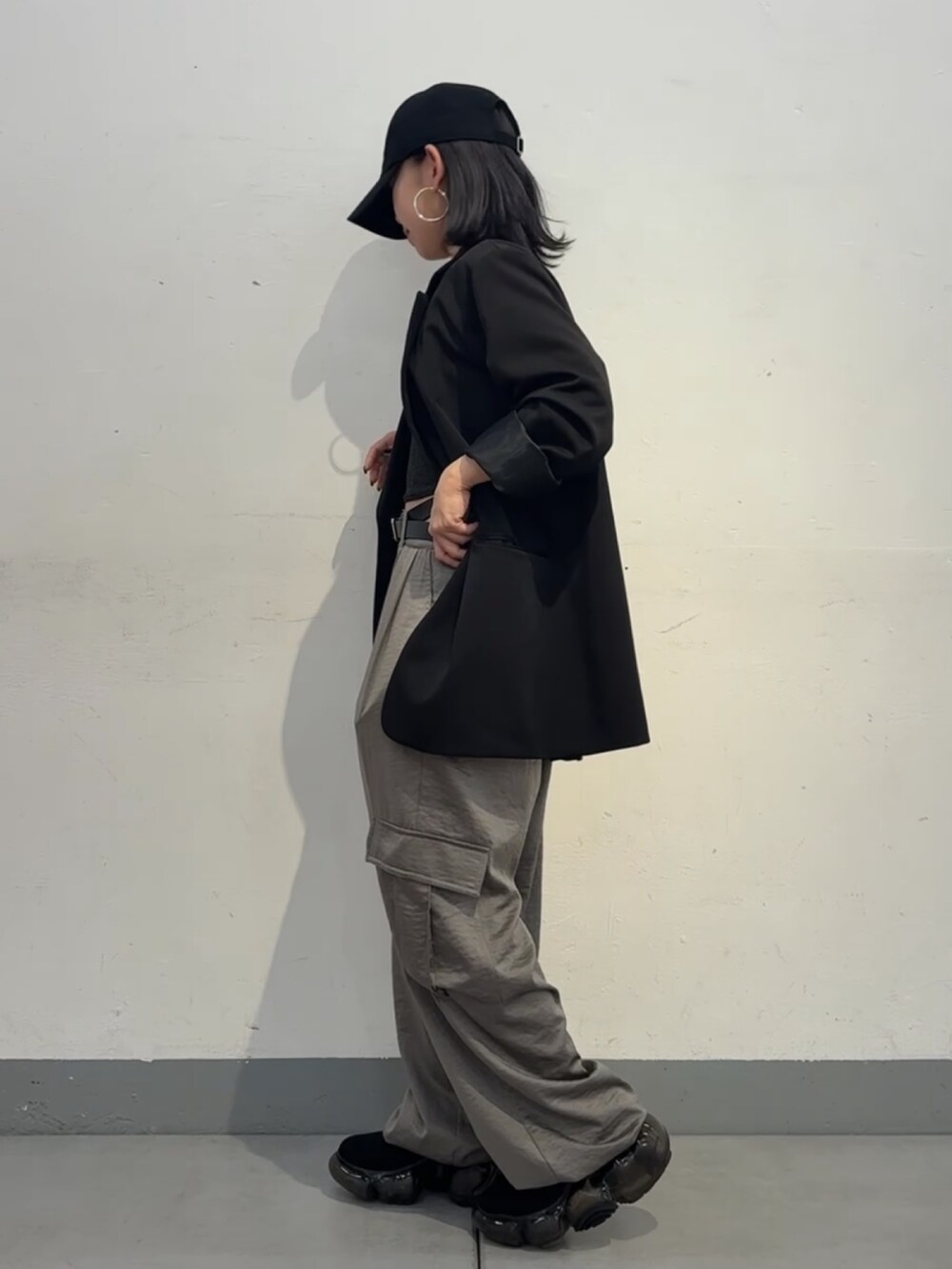 グレー系のカーゴパンツ、ブラック系のテーラードジャケット、ブラック系のキャップを着用したレディースの秋コーディネートの2枚目の写真