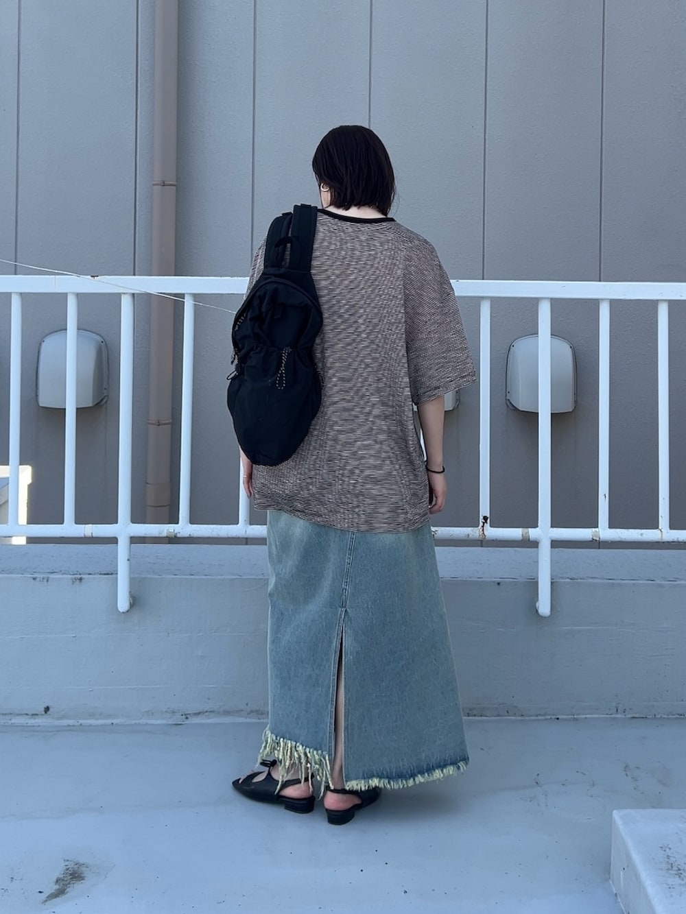 ブラック系のTシャツ/カットソー、ブルー系のスカート、ブラック系のサンダルを着用したレディースの春コーディネートの3枚目の写真