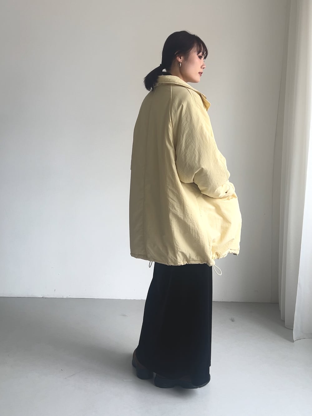 イエロー系のダウンジャケット/コート、グレー系のニット/セーター、ブラック系のスカートを着用したレディースの秋コーディネートの2枚目の写真