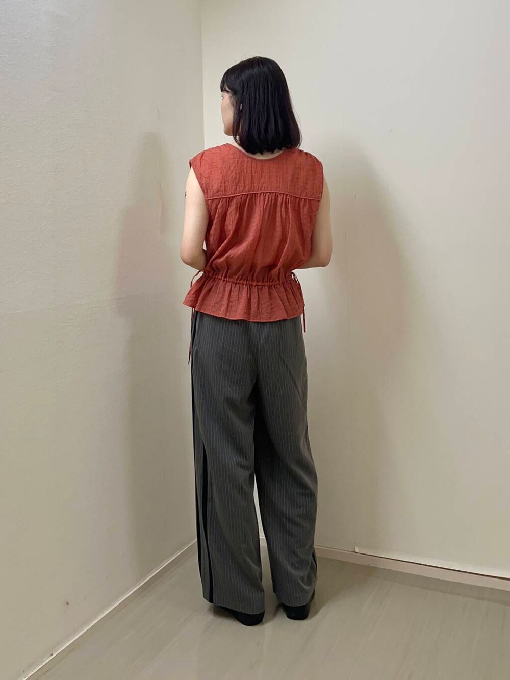 ブラック系のサンダル、グレー系のその他パンツ、オレンジ系のシャツ/ブラウスを着用したレディースの夏コーディネートの2枚目の写真