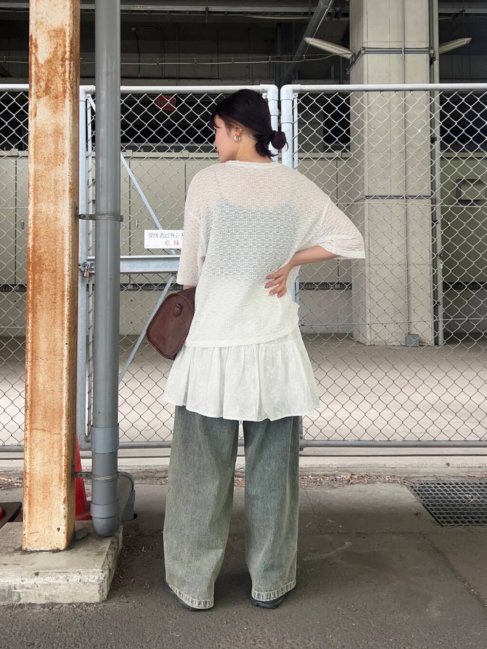 ブラウン系のボストンバッグ、ブルー系のデニムパンツ、ホワイト系のスカートを着用したレディースの春コーディネートの2枚目の写真