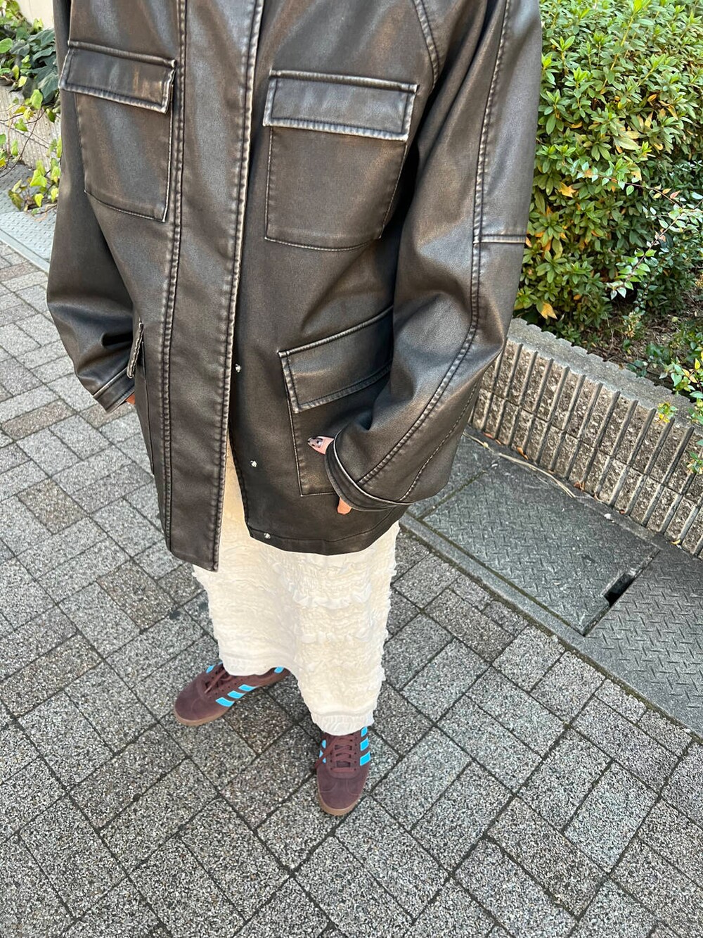 ホワイト系のスカート、ブラック系のその他アウター、ブラウン系のスニーカーを着用したレディースの冬コーディネートの3枚目の写真