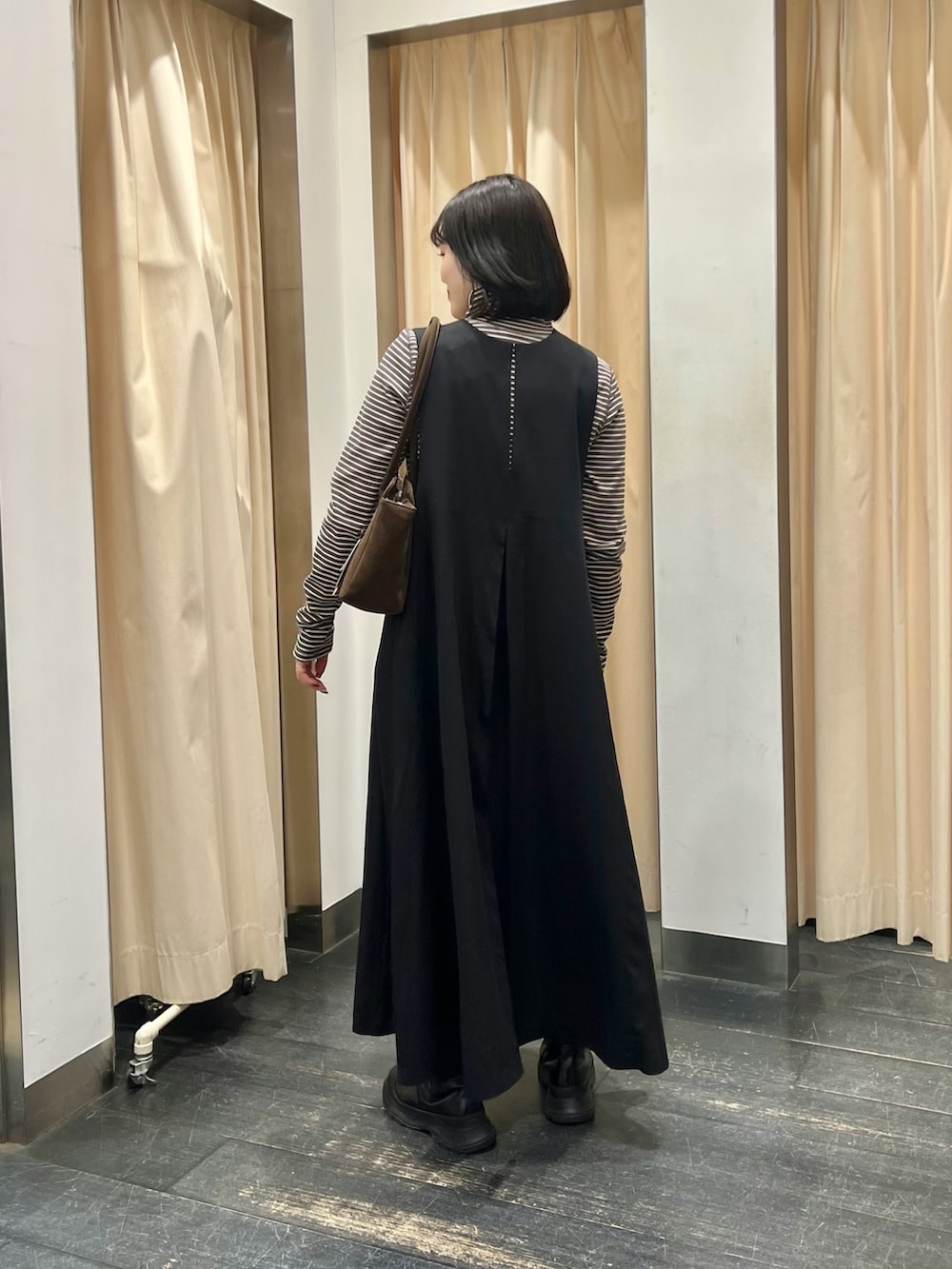 グレー系のTシャツ/カットソー、ブラウン系のボストンバッグ、ブラック系のワンピースを着用したレディースの冬コーディネートの2枚目の写真