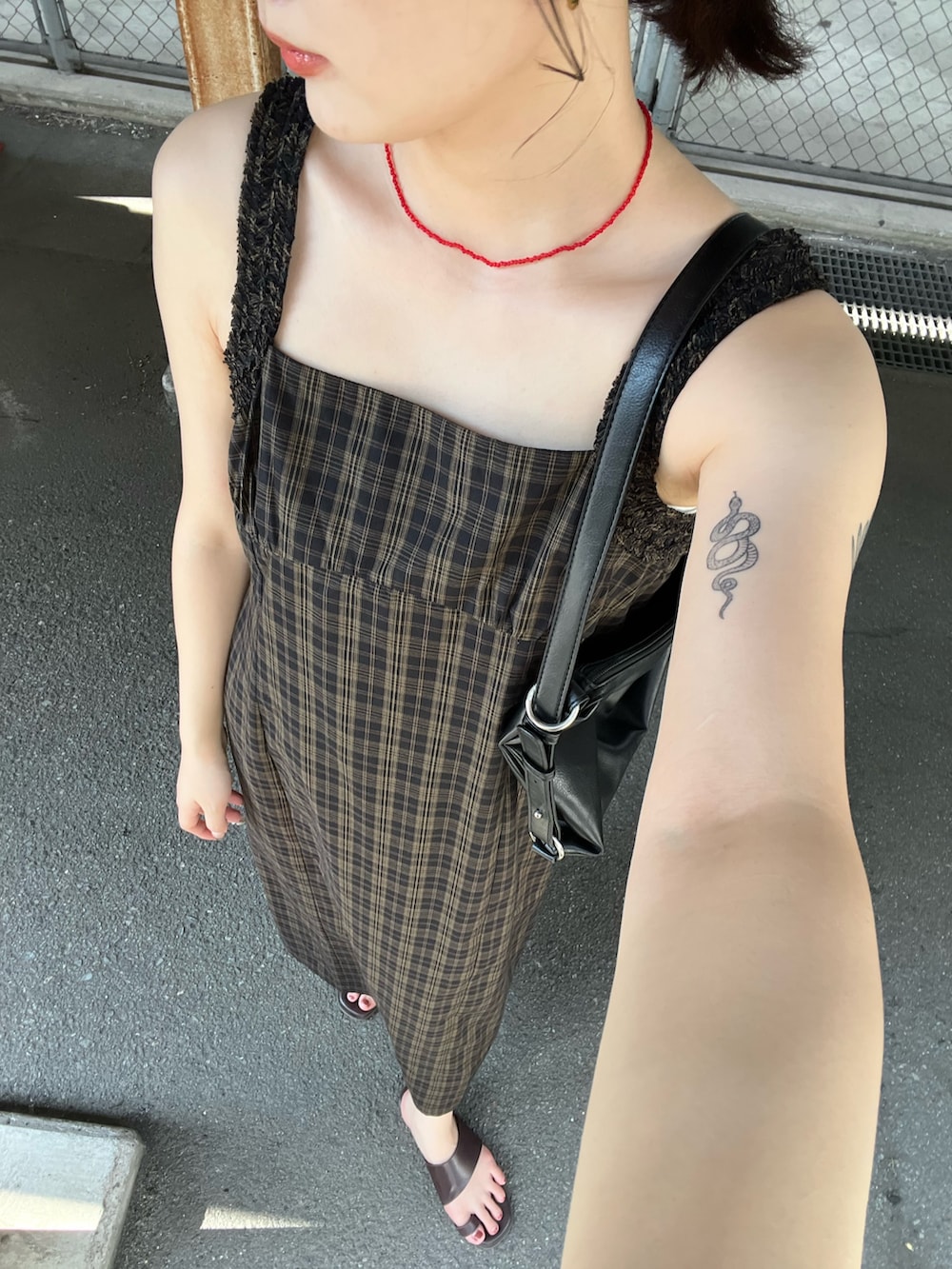 ブラック系のワンピース、ブラック系のショルダーバッグを着用したレディースの夏コーディネートの2枚目の写真