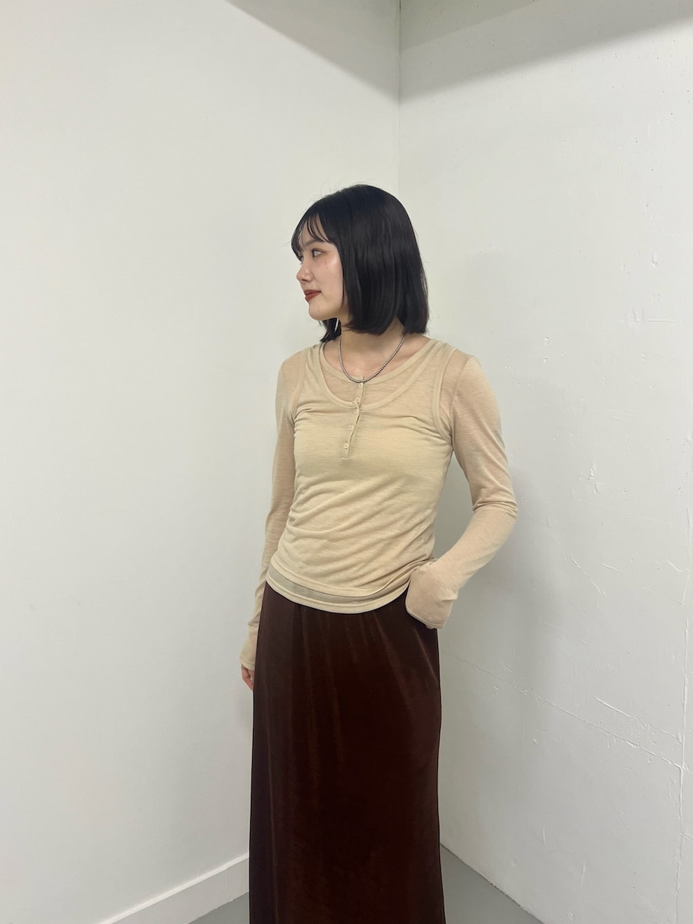 ベージュ系のTシャツ/カットソー、ブラウン系のスカートを着用したレディースの冬コーディネートの2枚目の写真