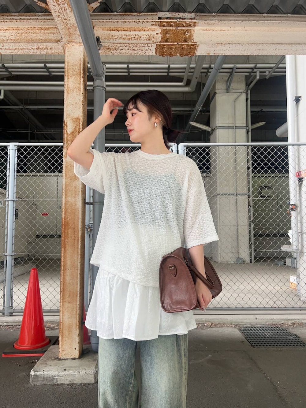 ブラウン系のボストンバッグ、ブルー系のデニムパンツ、ホワイト系のスカートを着用したレディースの春コーディネートの3枚目の写真