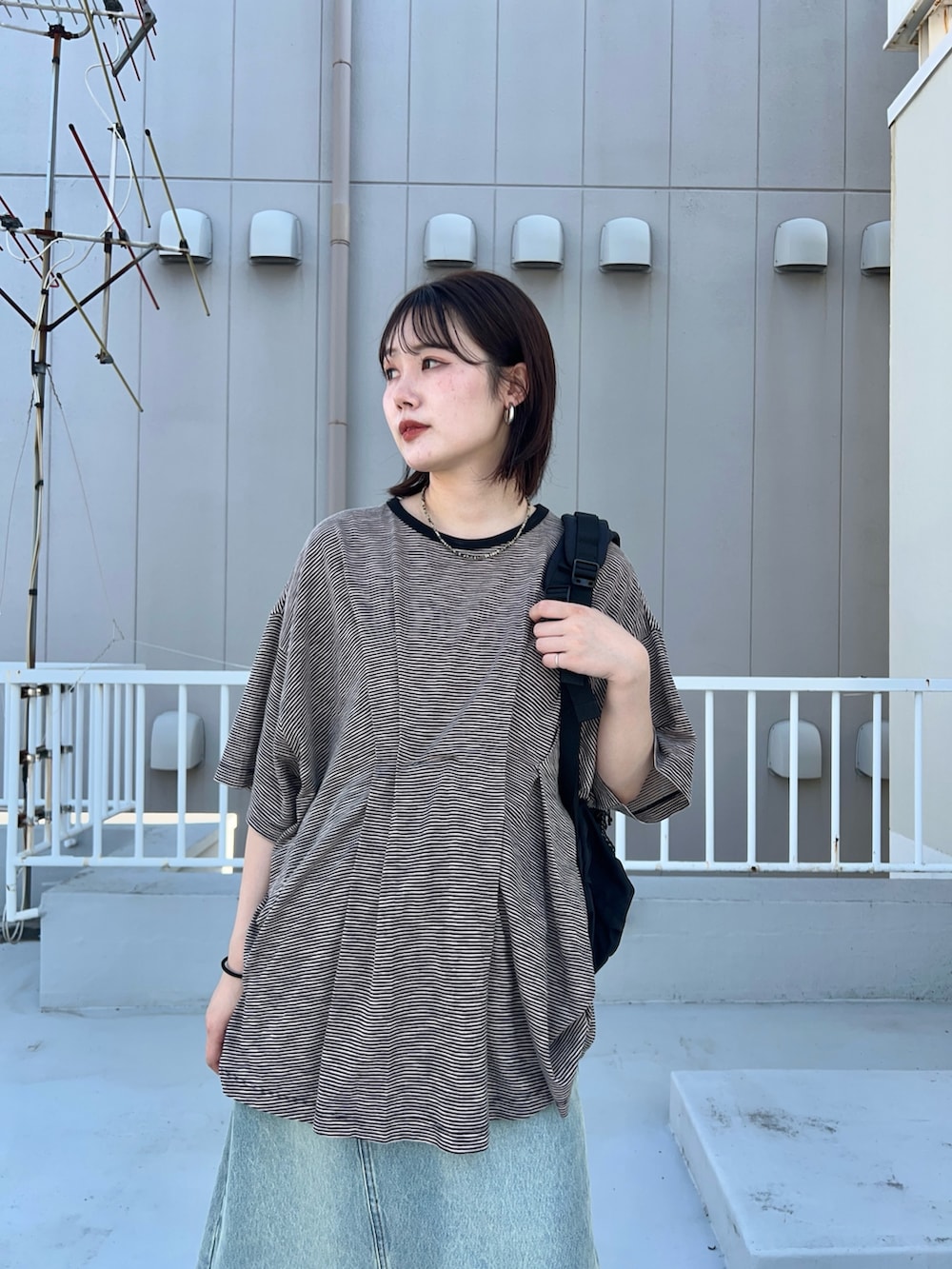 ブラック系のTシャツ/カットソー、ブルー系のスカート、ブラック系のサンダルを着用したレディースの春コーディネートの2枚目の写真