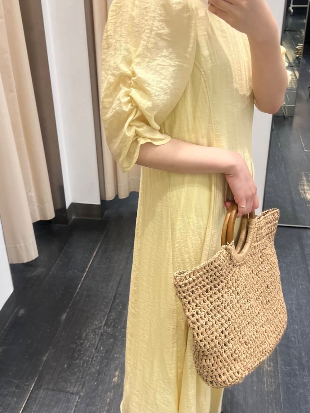 ベージュ系のトートバッグ、イエロー系のワンピース、ブラック系のサンダルを着用したレディースの夏コーディネートの2枚目の写真