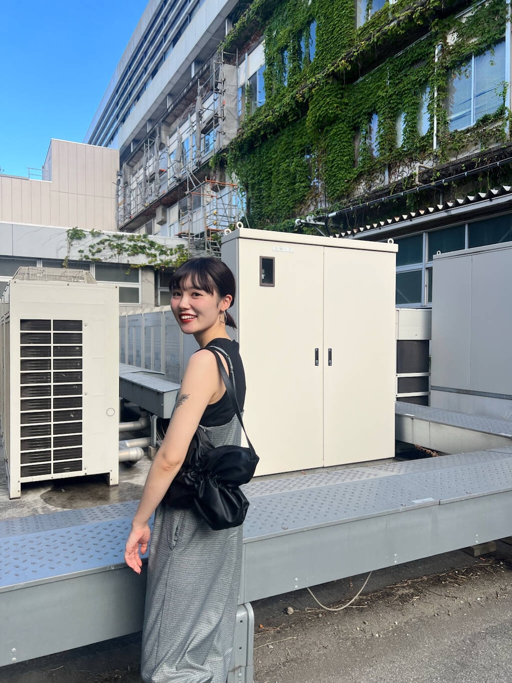 ブラック系のハンドバッグ、ブラック系のTシャツ/カットソー、グレー系のサロペット/オーバーオールを着用したレディースの夏コーディネートの2枚目の写真