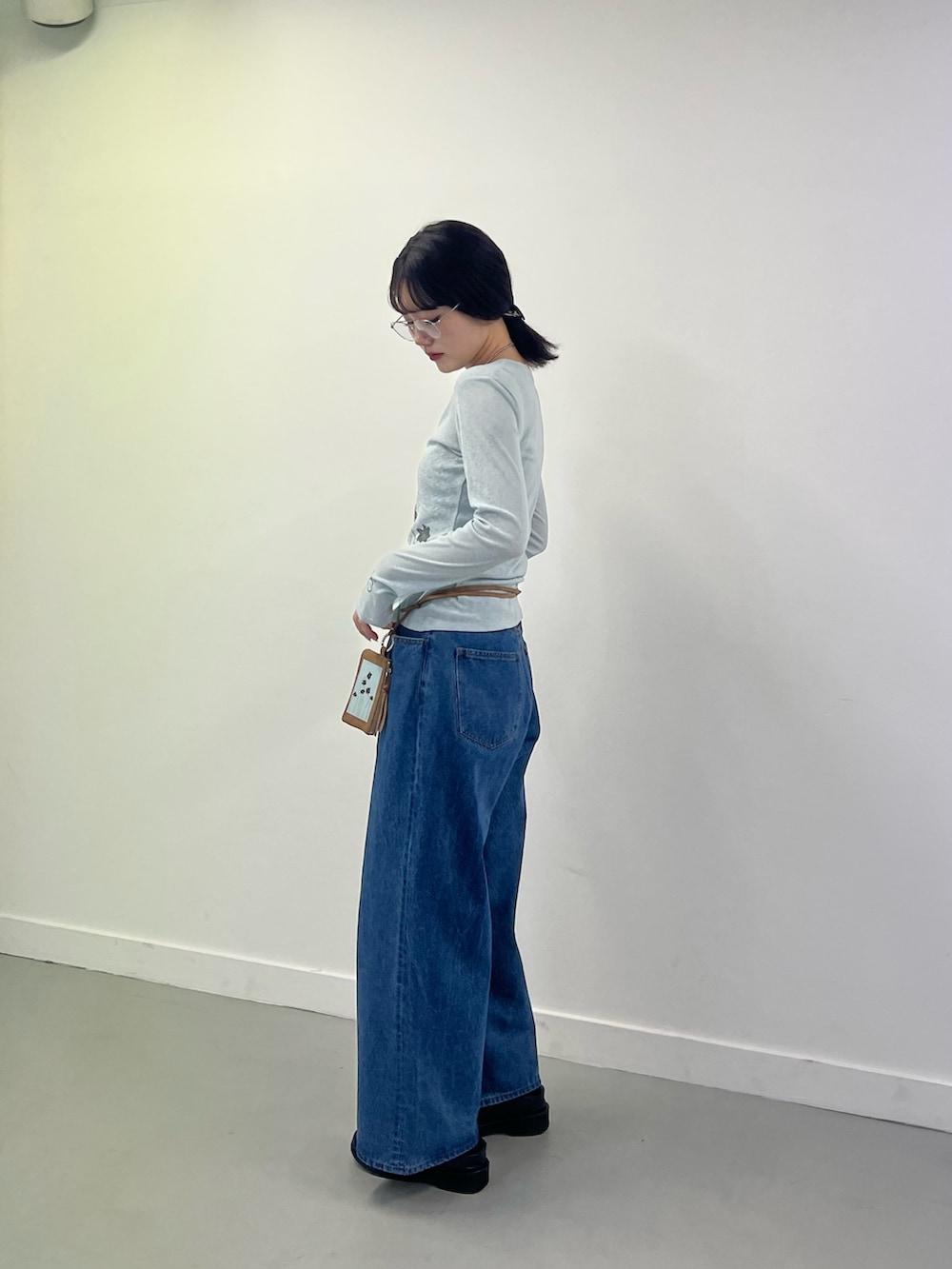 ブルー系のTシャツ/カットソー、ブルー系のデニムパンツ、ブラウン系のポーチを着用したレディースの秋コーディネートの2枚目の写真
