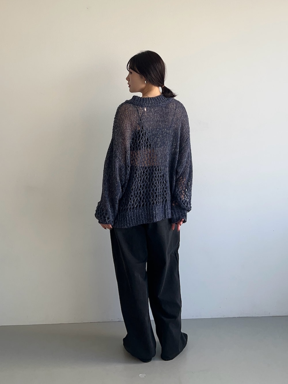 ブルー系のニット/セーター、ブラック系のデニムパンツ、ブラック系のスニーカーを着用したレディースの秋コーディネートの2枚目の写真