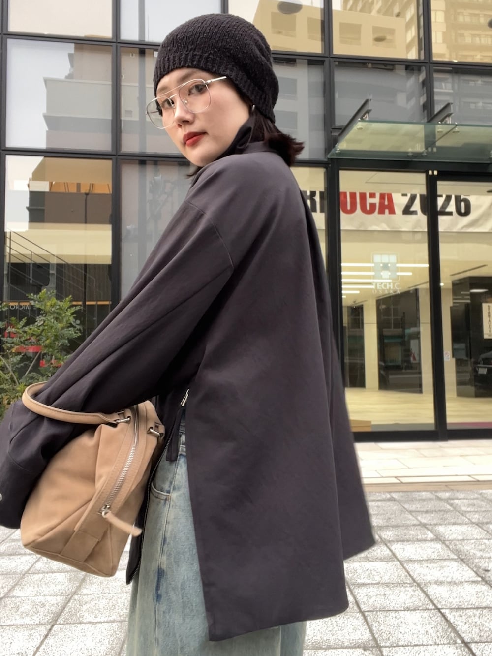 グレー系のその他アウター、ブルー系のデニムパンツ、ベージュ系のボストンバッグを着用したレディースの冬コーディネートの2枚目の写真