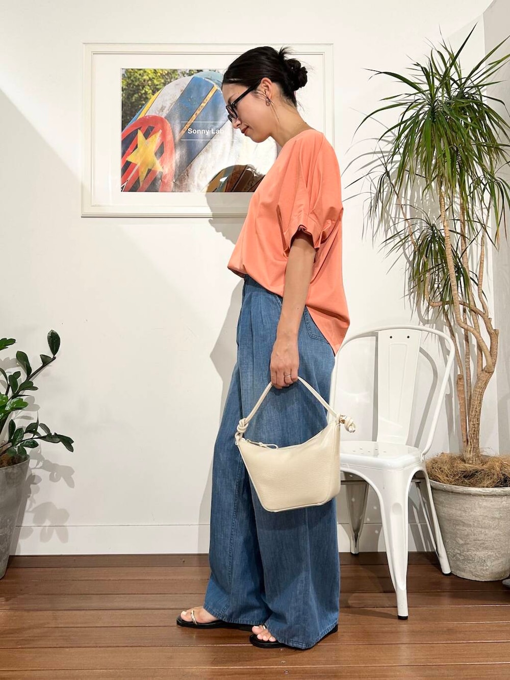 ホワイト系のショルダーバッグ、オレンジ系のTシャツ/カットソー、ブルー系のデニムパンツを着用したレディースの夏コーディネートの2枚目の写真