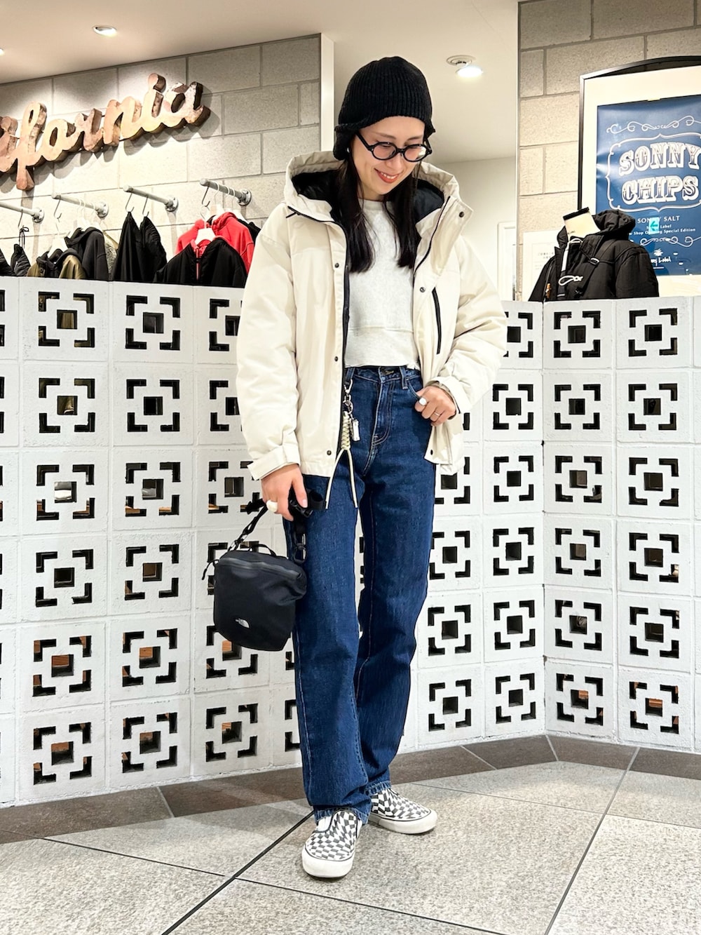 ブラック系のショルダーバッグ、ホワイト系のダウンジャケット/コート、ブルー系のデニムパンツを着用したレディースの冬コーディネートの2枚目の写真