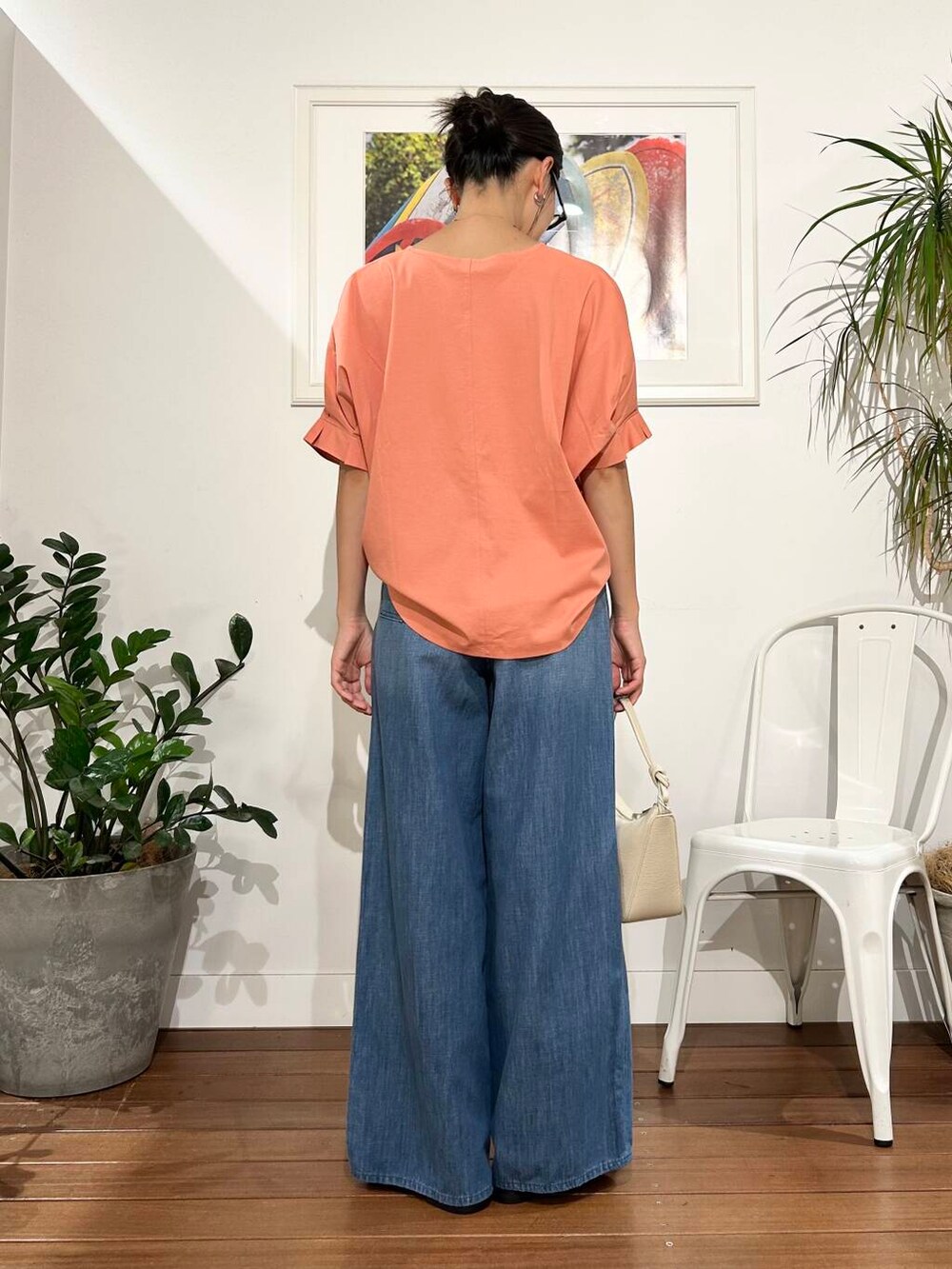 ホワイト系のショルダーバッグ、オレンジ系のTシャツ/カットソー、ブルー系のデニムパンツを着用したレディースの夏コーディネートの3枚目の写真