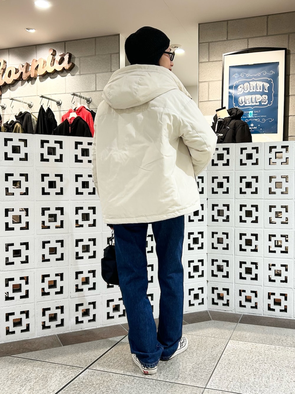 ブラック系のショルダーバッグ、ホワイト系のダウンジャケット/コート、ブルー系のデニムパンツを着用したレディースの冬コーディネートの4枚目の写真