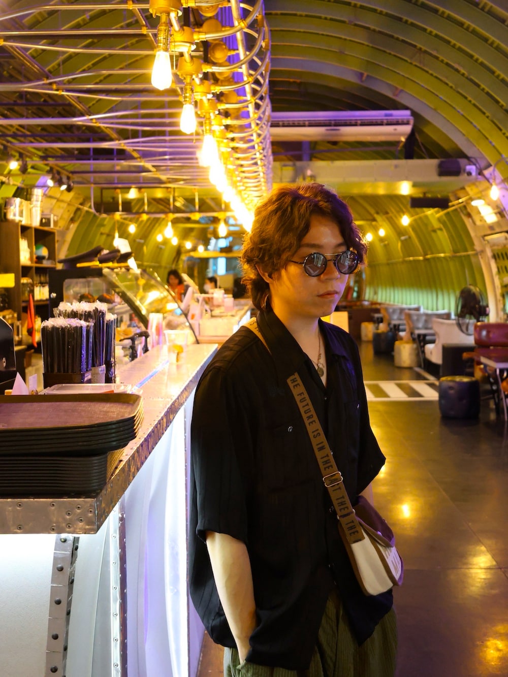 ブラック系のトップス、グリーン系のパンツ、ブラック系のスニーカーを着用したメンズの夏コーディネートの2枚目の写真