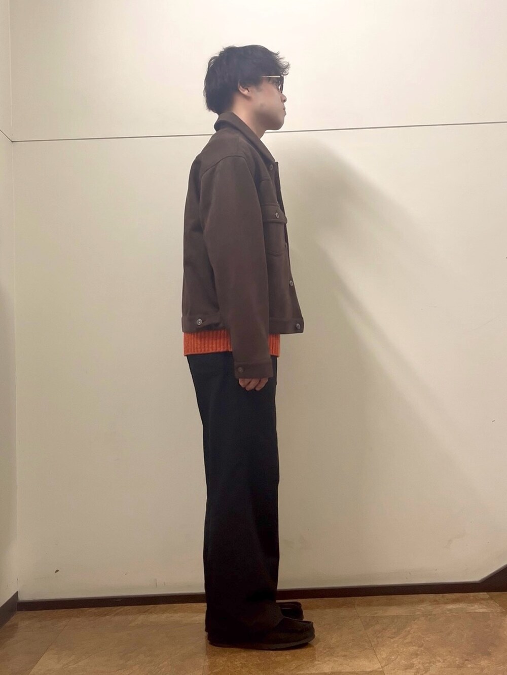 オレンジ系のニット/セーター、ブラウン系のカバーオールを着用したメンズの秋コーディネートの2枚目の写真