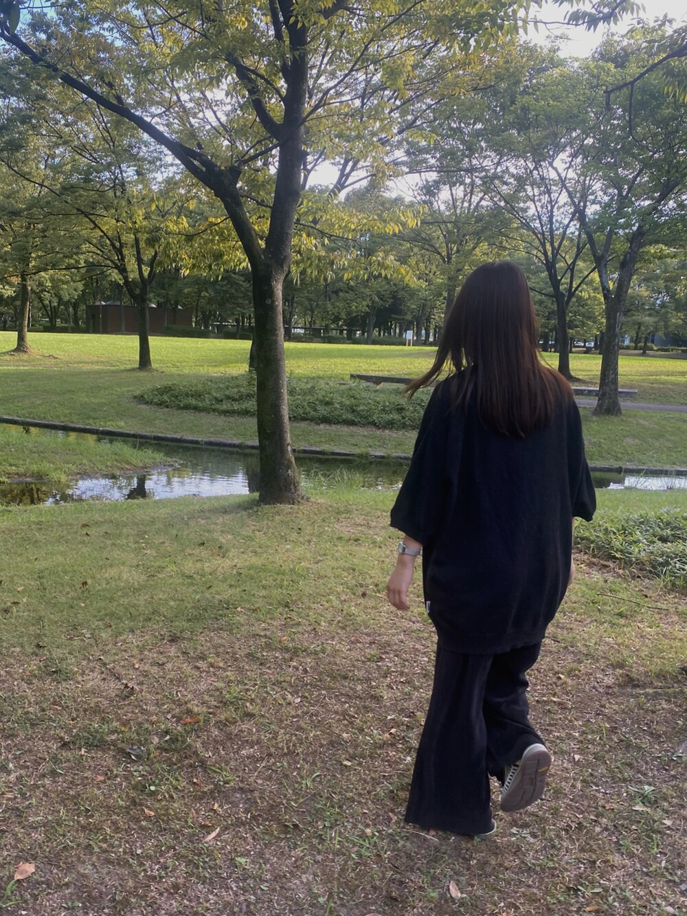 ホワイト系のサンダル、ブラック系のその他パンツ、ブラック系のTシャツ/カットソーを着用したレディースの秋コーディネートの2枚目の写真