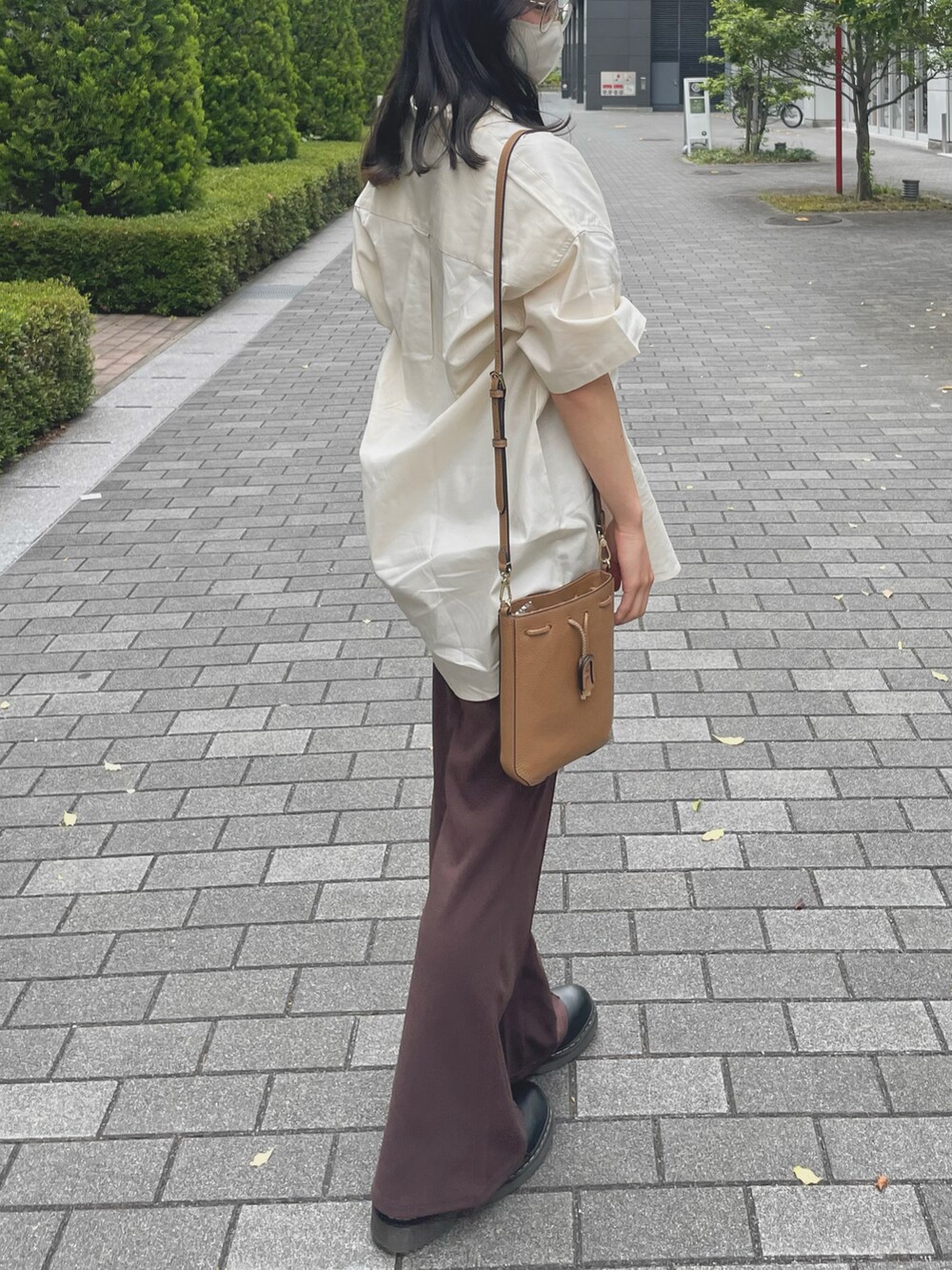 ブラウン系のスラックス、ホワイト系のシャツ/ブラウス、ブラウン系のショルダーバッグを着用したレディースの夏コーディネートの2枚目の写真