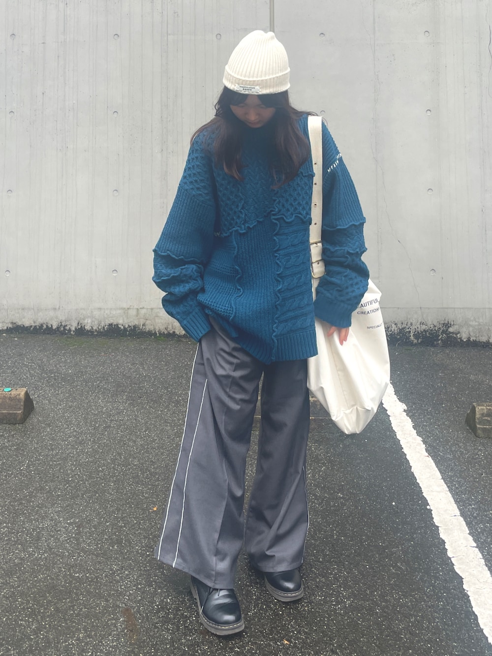 ブルー系のニット/セーター、グレー系のスラックス、ホワイト系のトートバッグを着用したレディースの秋コーディネートの3枚目の写真